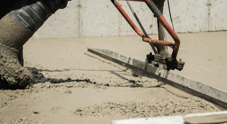 Worker levelling fresh screed with a power screed